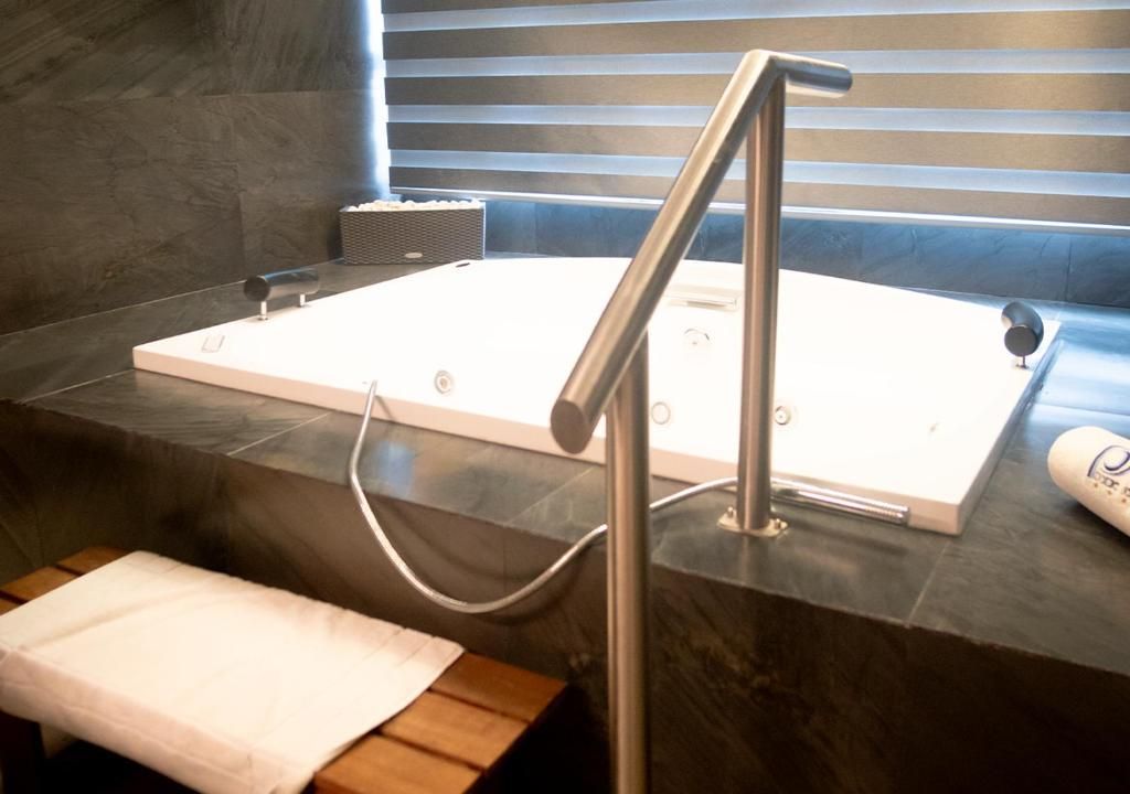 Un baño moderno con una bañera grande, un banco de madera y un perchero para toallas.