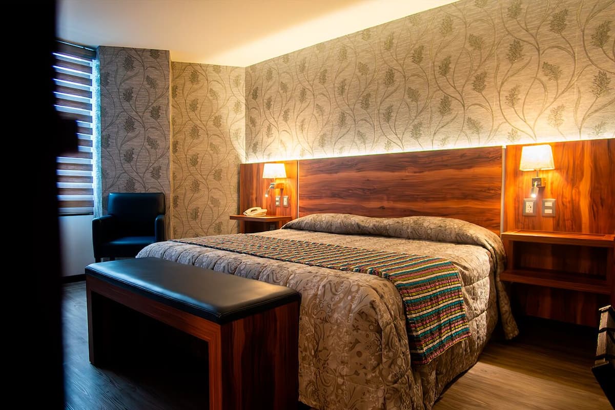 A neatly arranged bedroom with a bed, bedside tables, a bench, and a chair.