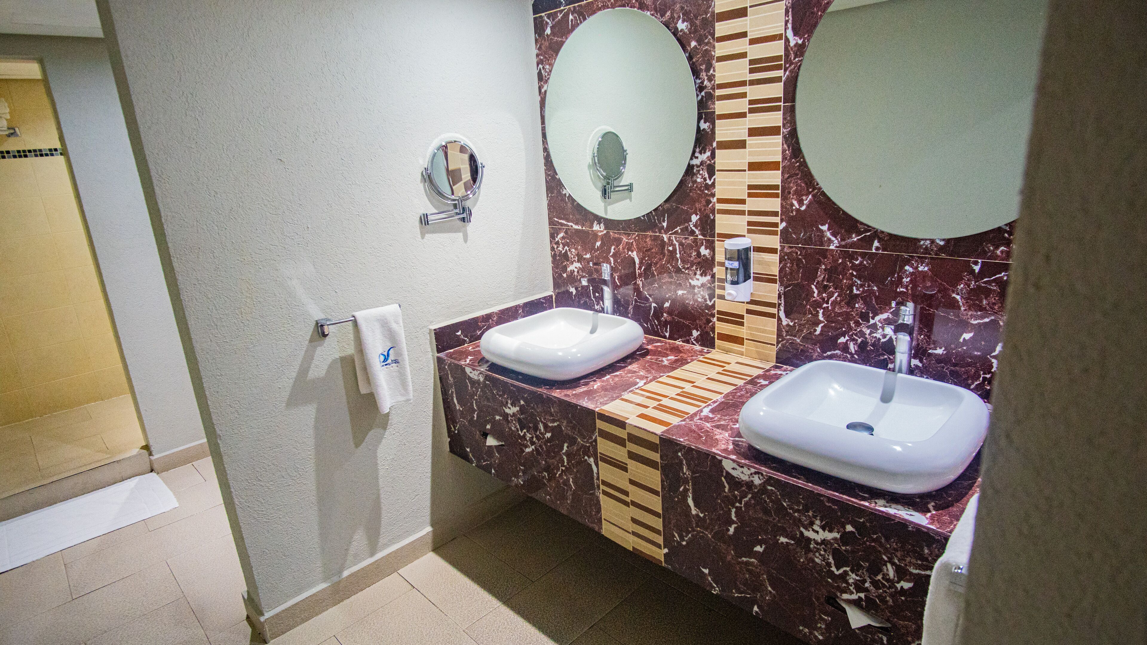 A bathroom with two sinks, marble backsplash, and a towel rack.