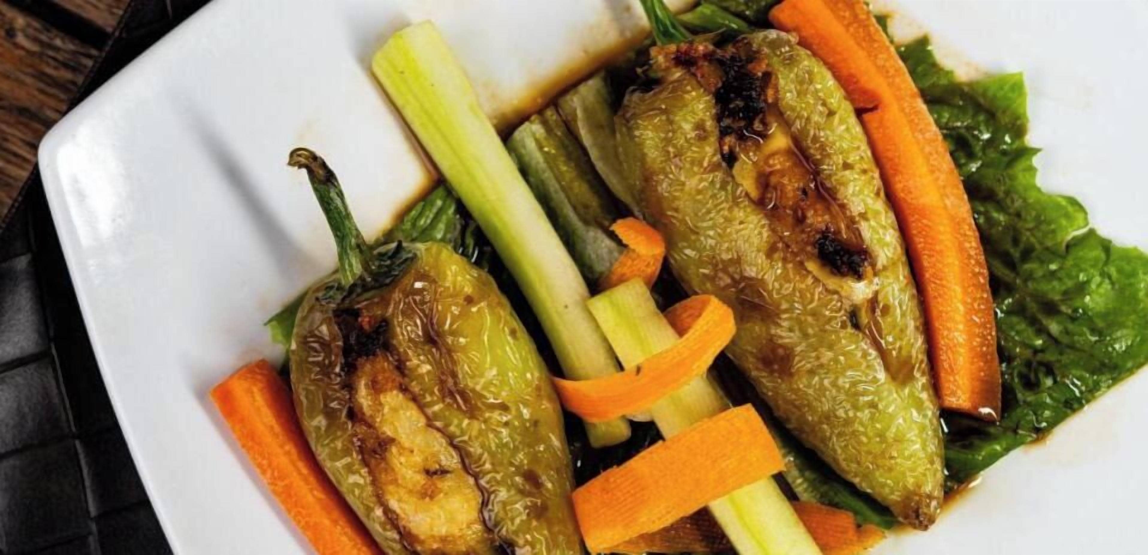 Une assiette de poivrons farcis, de carottes et de légumes verts.