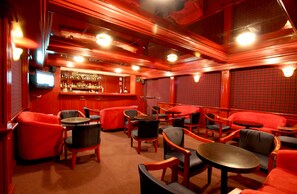A bar area with red and black furniture, a bar counter, and a television screen. - Hotel Parque Satelite (Tlalnepantla de Baz)