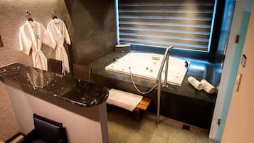 Un bagno moderno con una vasca da bagno ampia, un mobile toilette con specchio e due accappatoi bianchi su un appendiabiti.