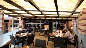 An outdoor dining area with tables and chairs, a wooden ceiling, and large windows. - Hotel Parque Satelite (Tlalnepantla de Baz)