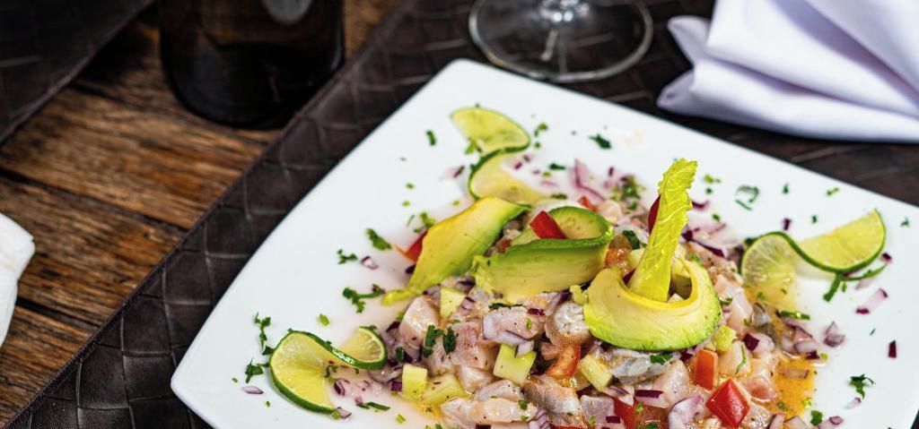 Prato branco com salada de frutos do mar sobre mesa escura e texturizada.