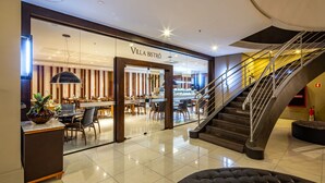 A modern interior with a staircase, a dining area, and a sign for "Villa Bistro".
