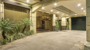 A hotel entrance with a glass door, potted plants, and a tiled floor.
