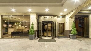 A hotel entrance with a revolving door, potted plants, and a sign reading "LAGHETTO VILLA MOUJA".