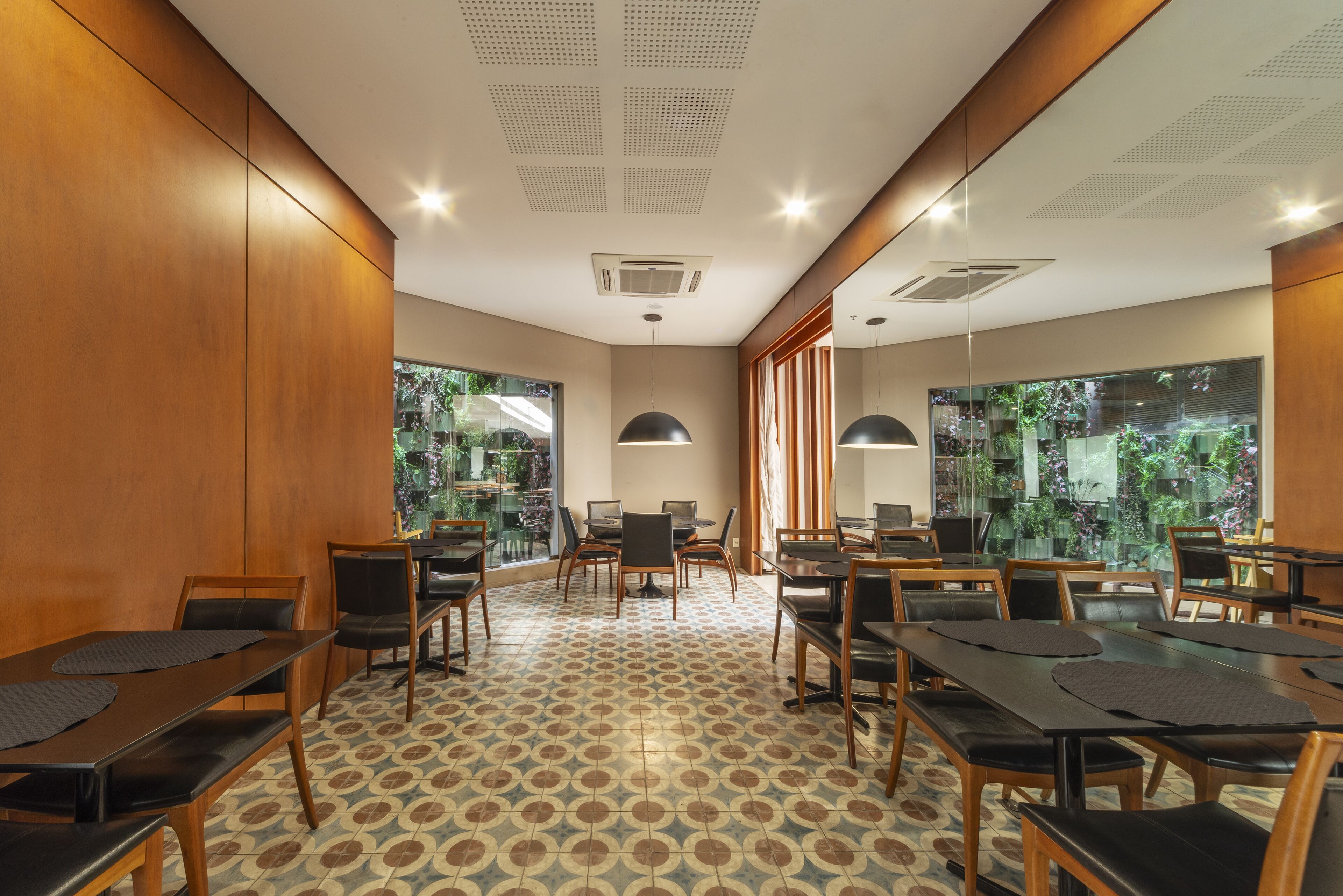 Uma sala de conferências com piso estampado, paredes de madeira e grandes janelas com vista para o verde.