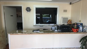 Una zona de recepció amb mostrador de marbre, un rellotge i una finestra.
