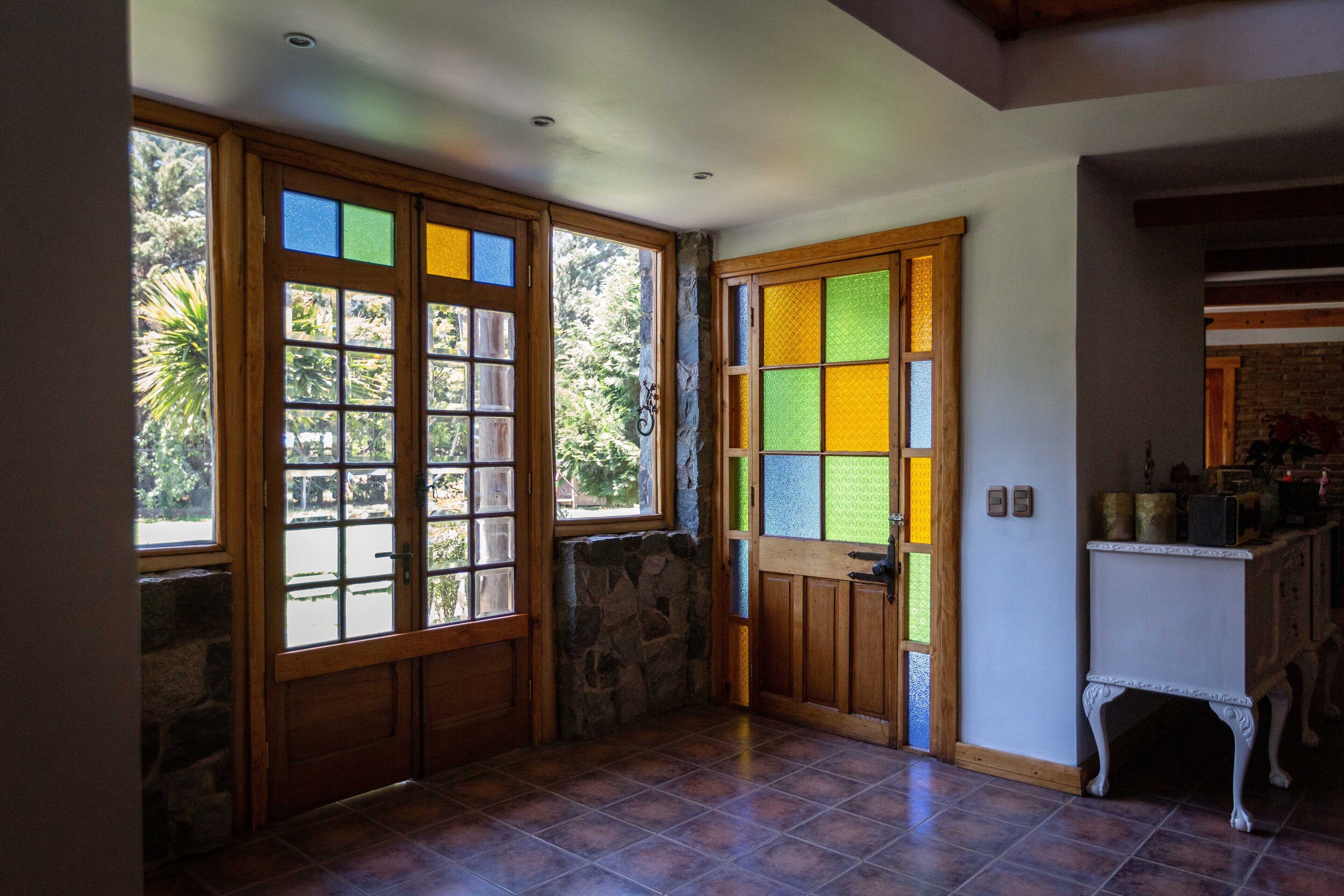 Une pièce avec un mur en pierre, une porte en bois ornée de panneaux de vitrail et un sol carrelé.