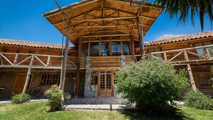 A rustic wooden building with a covered porch, stone foundation, and a large window.
