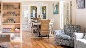A dining area with a wooden table, chairs, and a bookshelf filled with books. - Enchanted Cottages (Seaview)