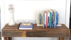 A wooden bench with a painting of a beach and books. - Enchanted Cottages (Seaview)