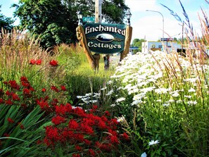 A sign for Enchanted Cottages with a rustic wooden post and a lamp post.