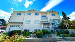 A two-story house with a garage, a front porch, and a well-maintained garden.