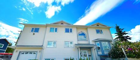 A two-story house with a garage, a front porch, and a well-maintained garden.