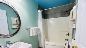A bathroom with a white sink, toilet, and shower. There is a mirror on the wall, and a towel rack with a white towel.