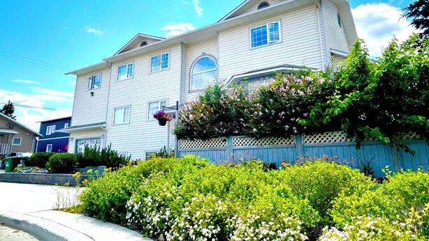 A two-story house with a white exterior, a front porch, and a wooden fence.