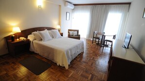 Una habitación de hotel con una cama grande, mesitas de noche, un escritorio y una silla.