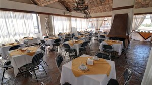 Un comedor con mesas redondas, sillas y chimenea.