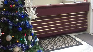 A reception area with a Christmas tree, a reception desk, and a window with a view of the outside. - Rider's Inn (Kamloops)