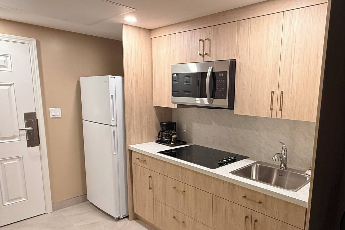 A compact kitchen with a built-in microwave, a stovetop, and a sink.