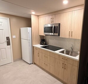 Una cocina compacta con microondas integrado, hornilla y lavaplatos.