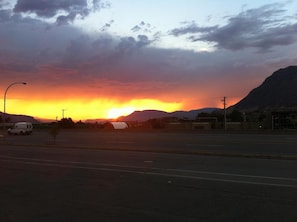 A sunset over a mountainous landscape with a road in the foreground.