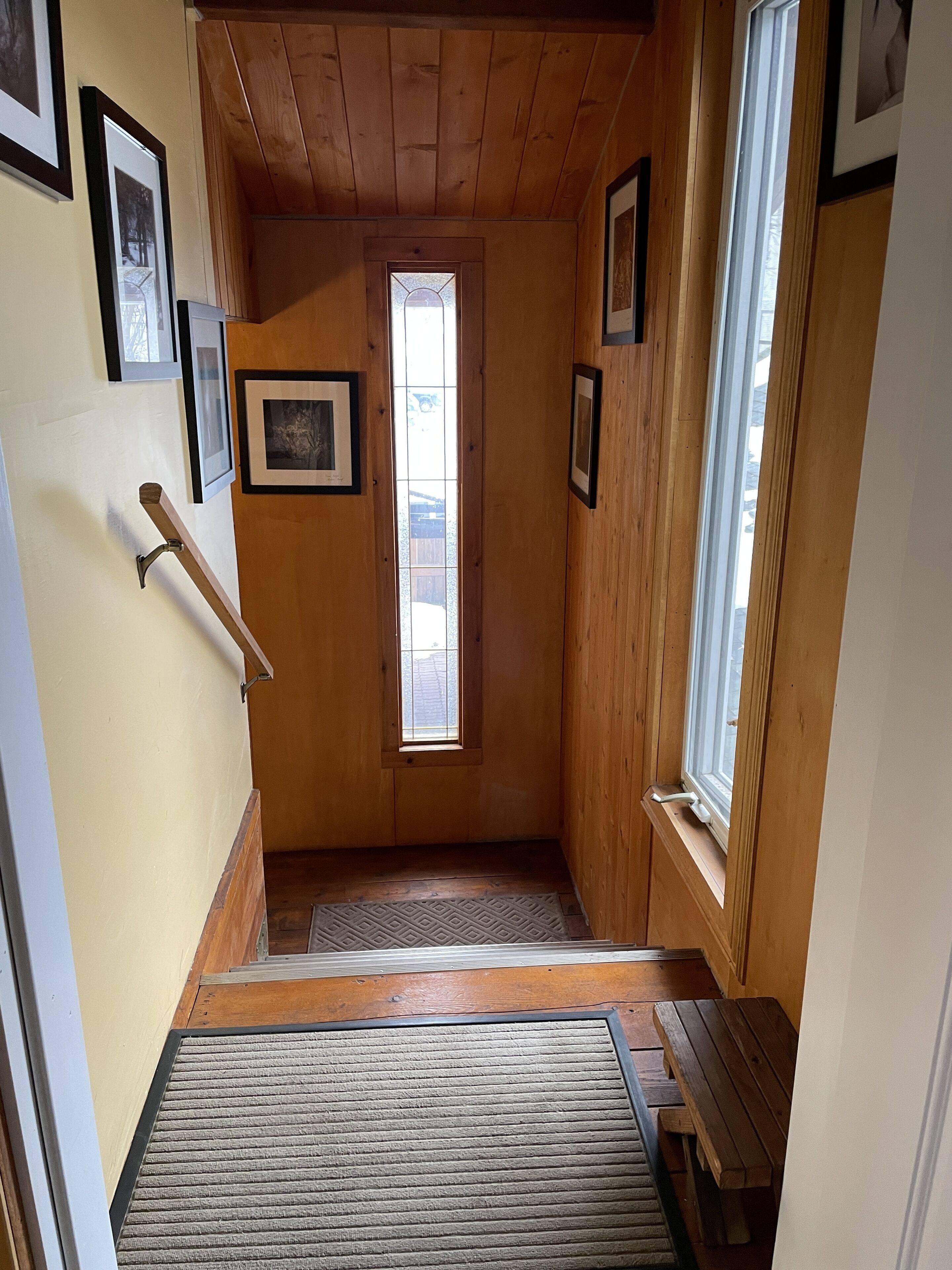 A wooden stairway with a handrail, a small window, and a door at the top.