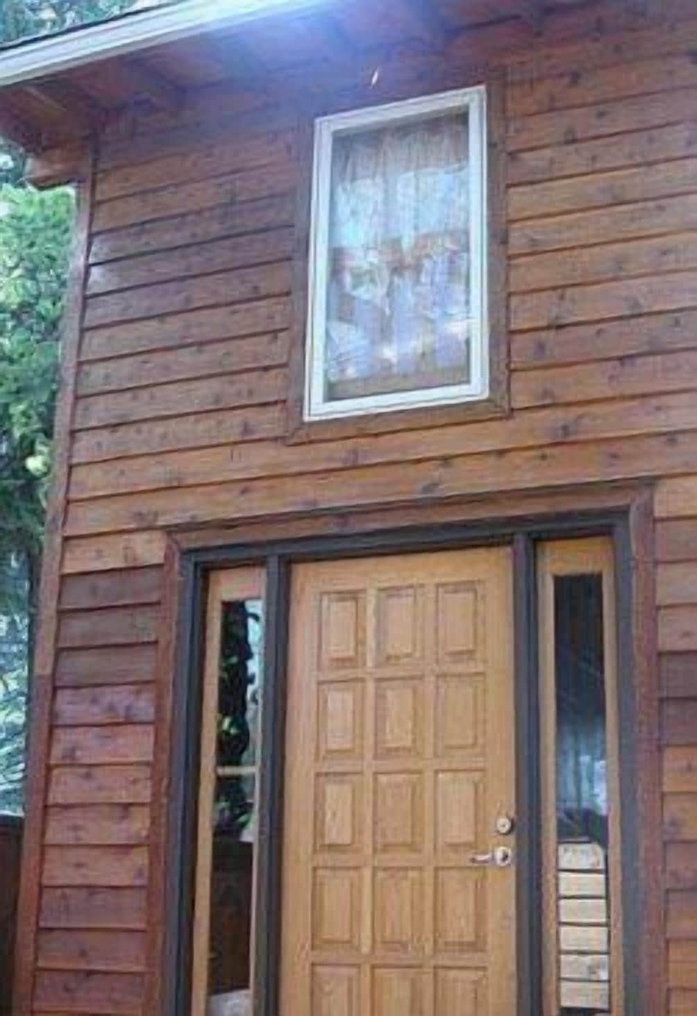 A wooden cabin with a central door and a window above it.