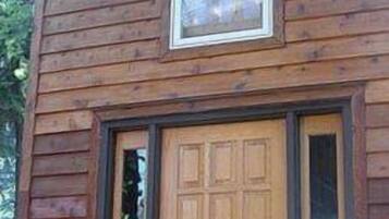 A wooden cabin with a central door and a window above it.