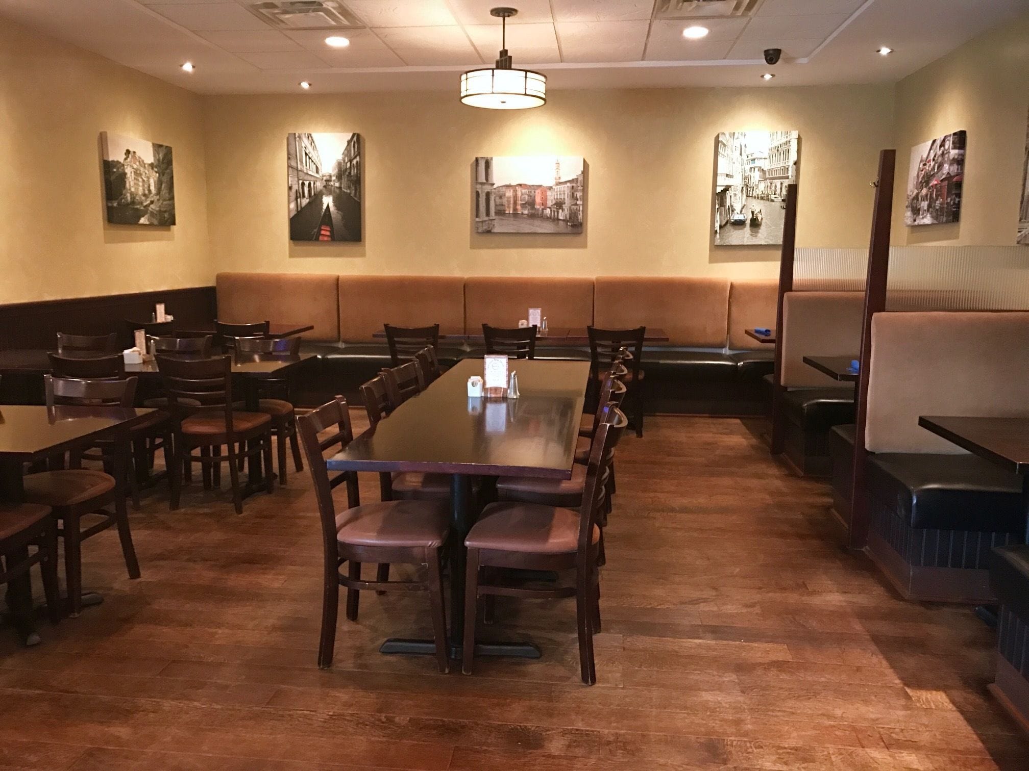 A restaurant with long communal tables and booths, featuring artwork on the walls.