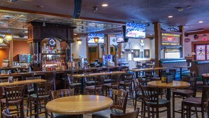 A bar with multiple seating areas, including round tables and booths, and a bar counter with a variety of bottles and a dartboard. - Park West Inn (Winnipeg)