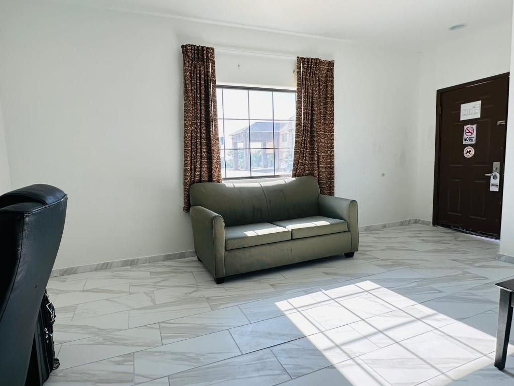 A room with a sofa, a door with a sign, and a window with curtains.