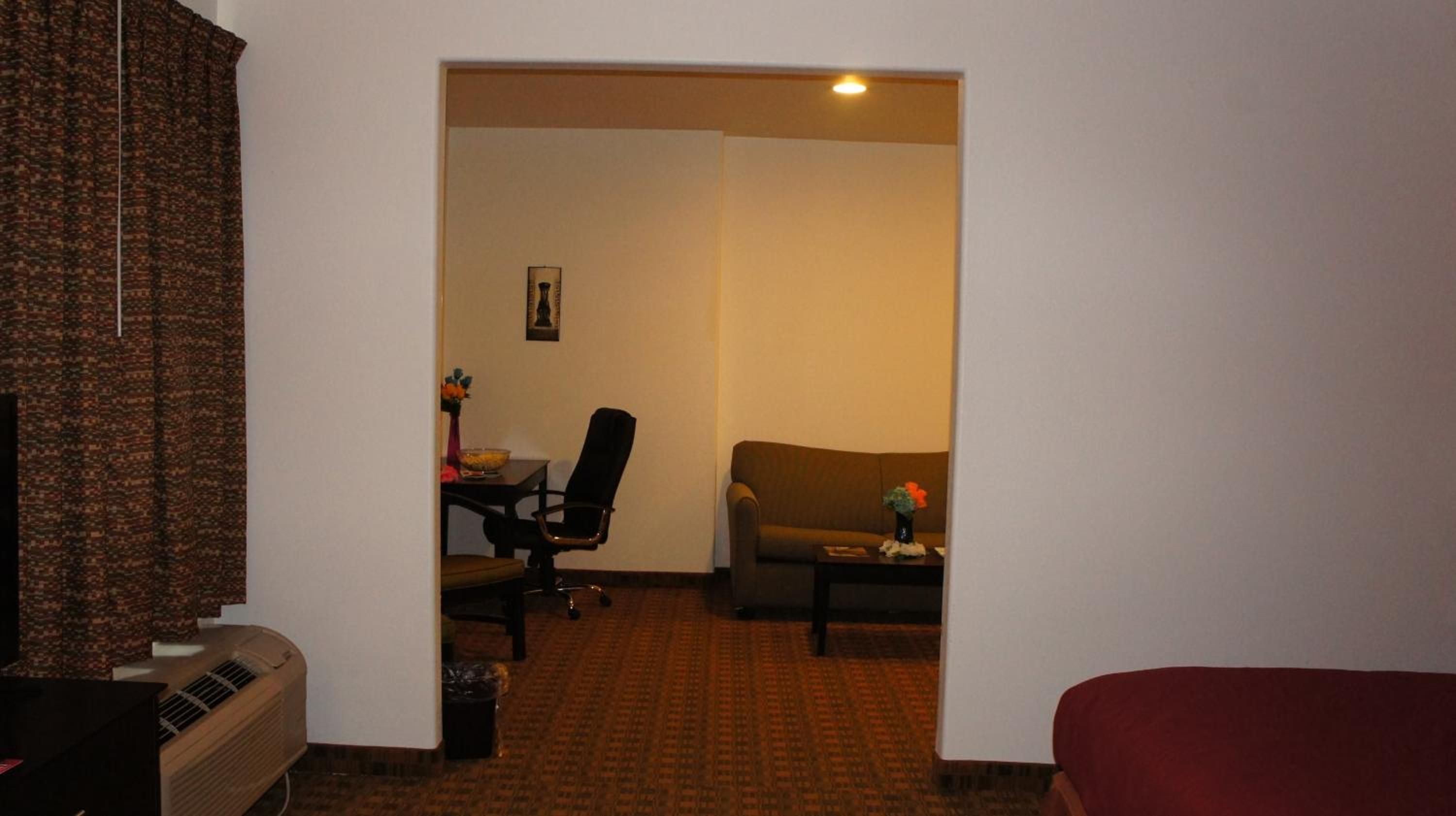 Habitació d'hotel amb un sofà, una taula petita amb un ram, una cadira i un escriptori amb un ordinador.