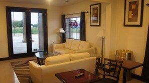 A living room with a sofa, a glass coffee table, a lamp, and a framed picture on the wall.