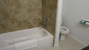 A bathroom with a bathtub, toilet, and a towel rack. - Lux Inn and Suites (Three Rivers)