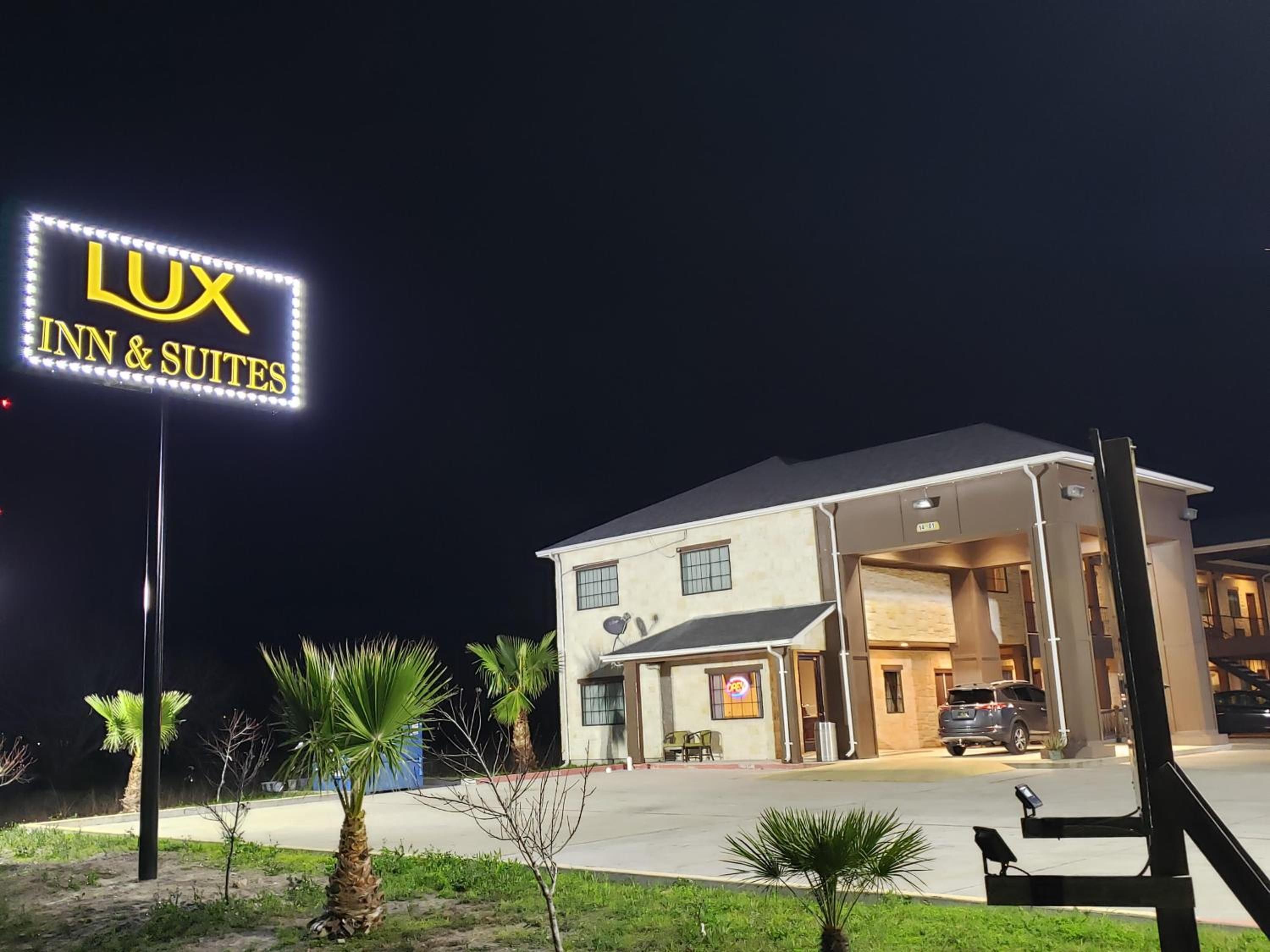 Un hôtel appelé « LUX INN & SUITES », avec une enseigne, un parking et une entrée.