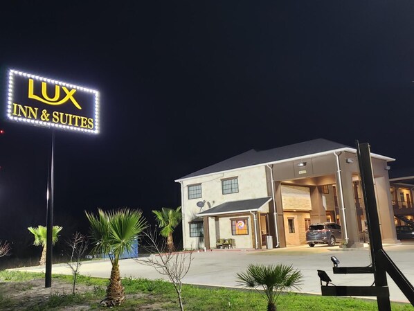 A hotel named 'LUX INN & SUITES' with a signboard, a parking area, and a building entrance.