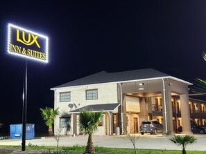 A hotel with a prominent illuminated sign reading "LUX INN & SUITES" at night.