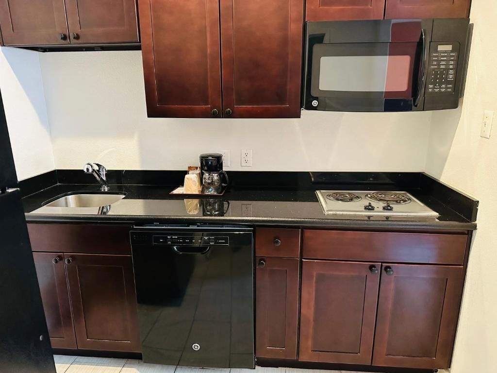A kitchen with a dishwasher, stove, microwave, and wooden cabinets.