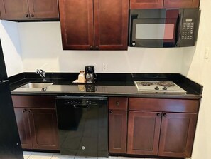 A kitchen with a dishwasher, stove, microwave, and wooden cabinets. - Lux Inn and Suites (Three Rivers)