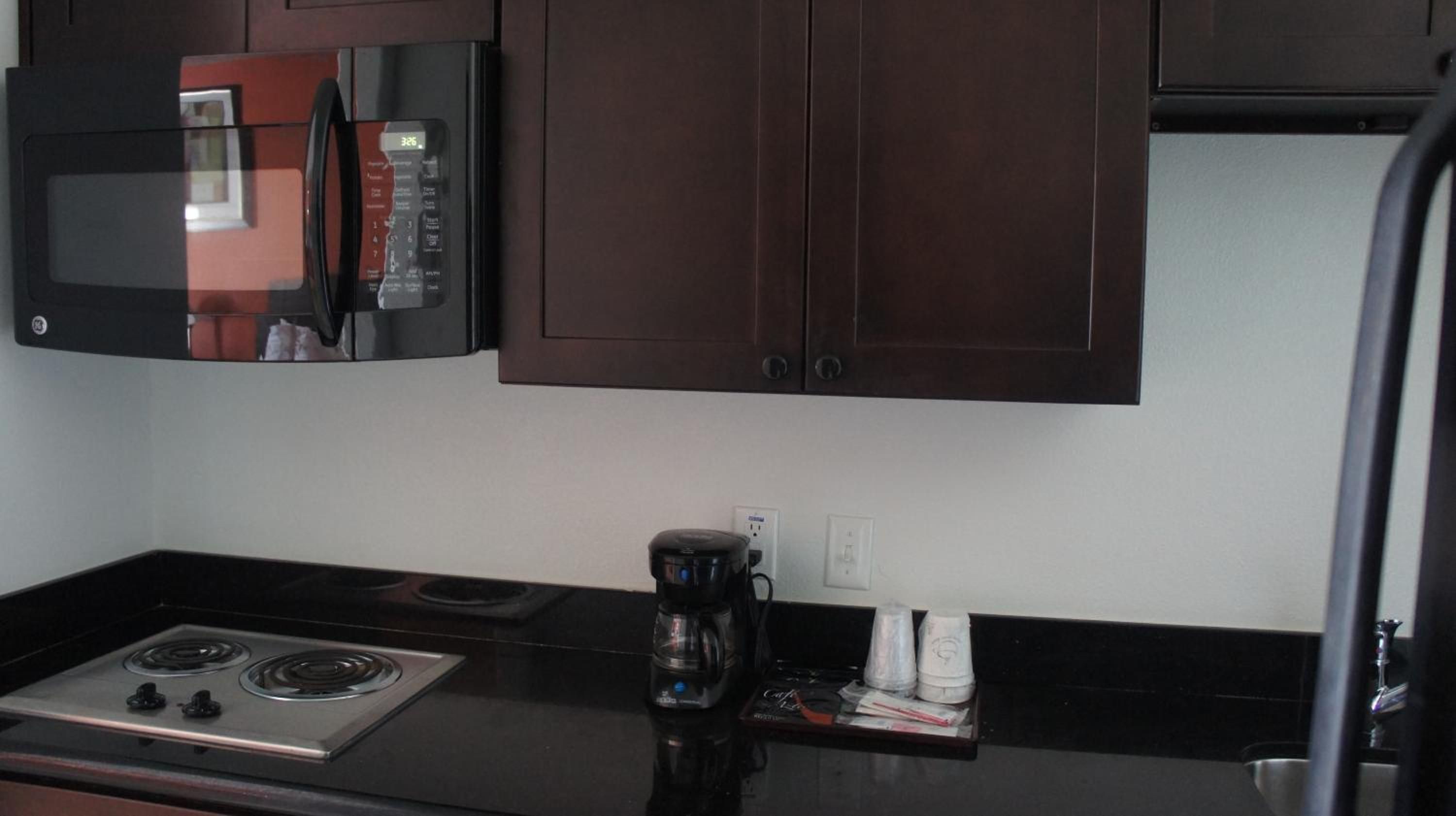A kitchenette with a microwave, stove, and coffee maker.