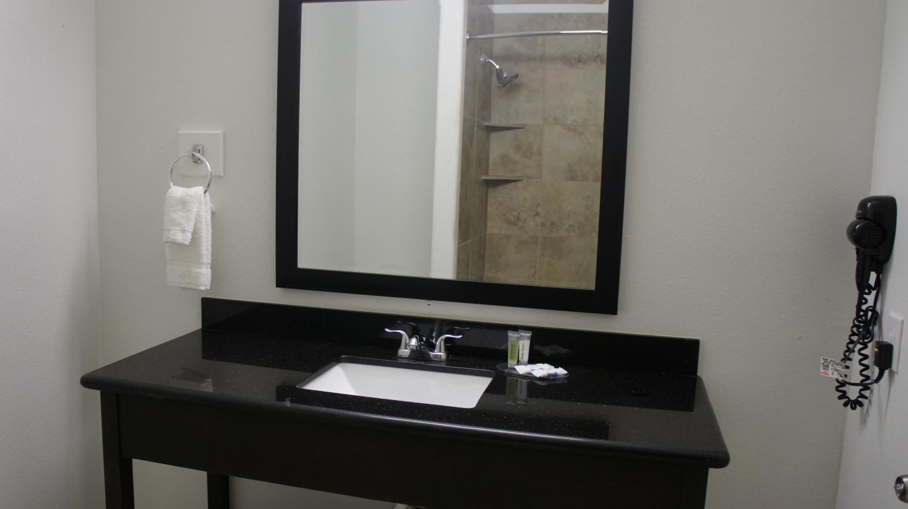 A bathroom with a black sink, a mirror, a towel rack, and a hairdryer.