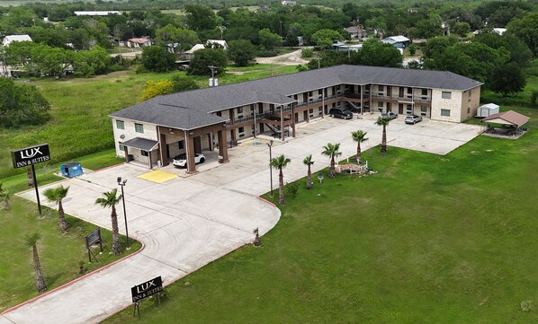 A LUX Inn & Suites with a two-story building, a covered parking area, and a landscaped lawn with palm trees.