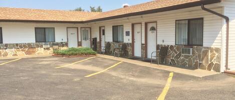 A motel with a parking lot, stone accents, and a tiled roof.