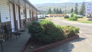 Ein Motel mit überdachter Veranda, Sitzgelegenheiten im Freien und Bergblick im Hintergrund.