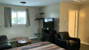 Ein Hotelzimmer mit Bett, Fernseher, Schreibtisch, Stuhl und einem Fenster mit Vorhängen.