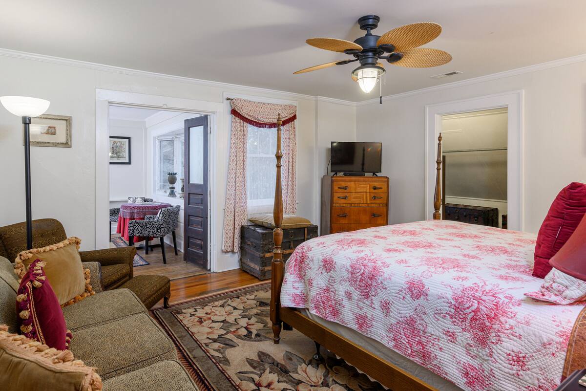 Une chambre à coucher comprenant un lit, une commode, un téléviseur et un ventilateur de plafond.