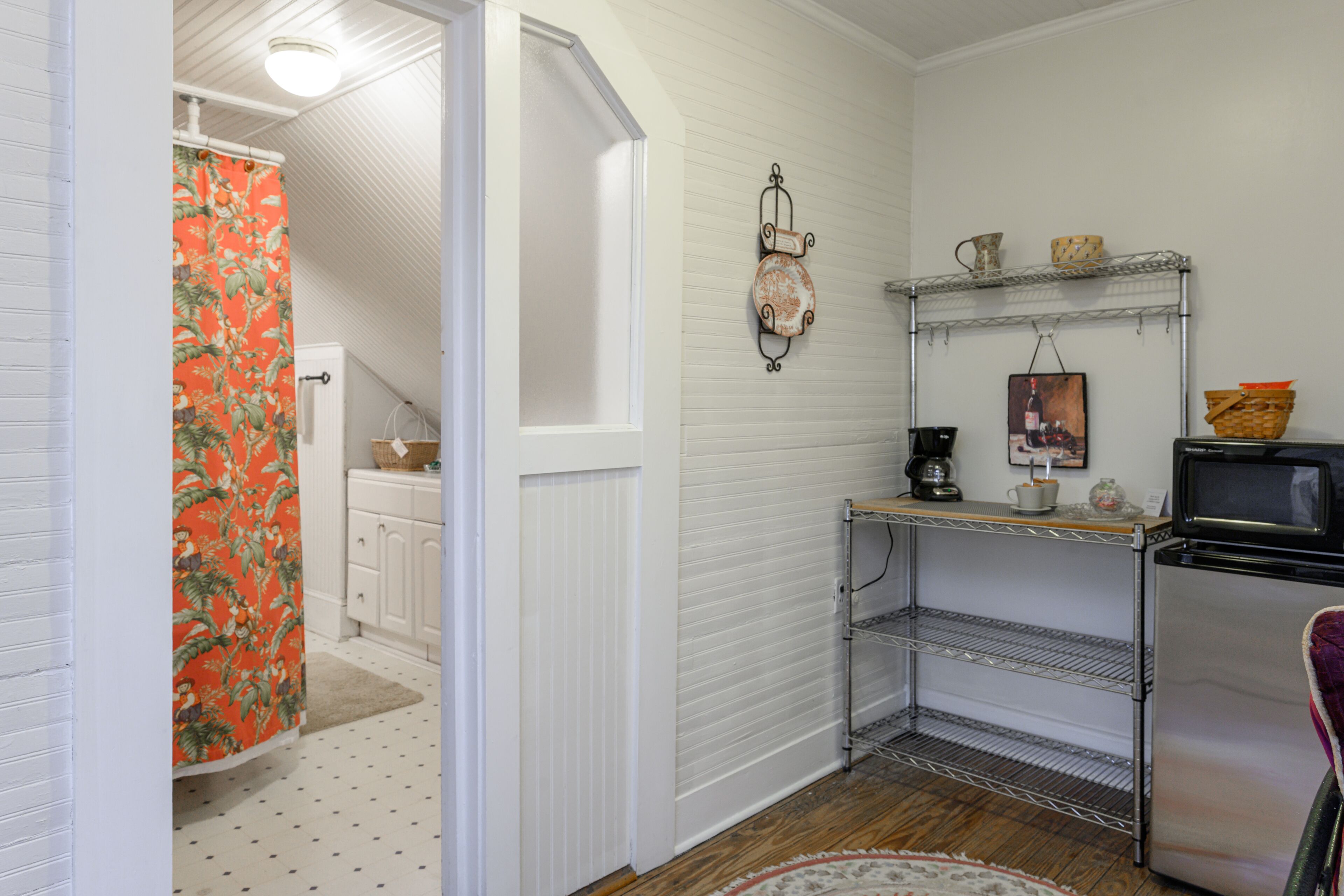 A compact kitchen with white cabinetry, a microwave, and a small refrigerator.